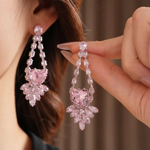 Gros plan de boucles d'oreilles en pierres roses en forme de cœur portées par un mannequin