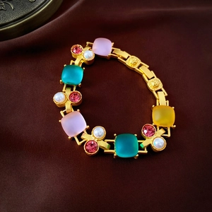 Detail of vintage gold chain with colorful gemstones and pearls on silk fabric