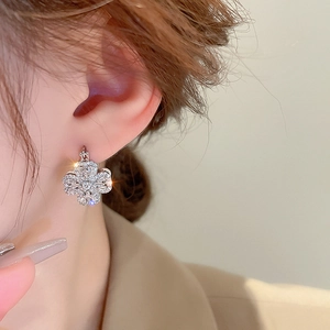 Detailed macro view of silver clover earrings with sparkling cubic zirconia on ears