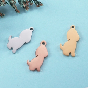 Three dog-shaped stainless steel charms in silver, rose gold, and gold on a blue background