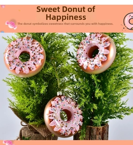 Close-up of pink and gold donut-shaped glass ornaments hanging on a Christmas tree