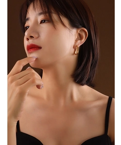 Close-up of minimalist gold U-shape huggie earrings on model with soft lighting