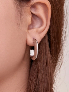 Detailed close-up of a silver U-shaped chunky hoop earring on a model ear