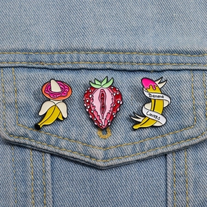 Close-up of enamel fruit brooches with banana and strawberry motifs on denim fabric