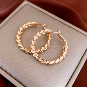 Macro shot of gold hoop earrings with twisted texture on a soft premium cushion
