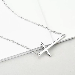 Minimalist silver cross pendant necklace with polished metal finish on white background