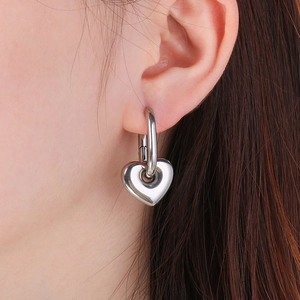 Gros plan d'une boucle d'oreille cœur en acier inoxydable argenté sur un mannequin