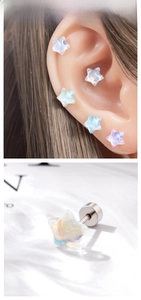 Detail showing iridescent star stud earrings with screw back on ear cartilage