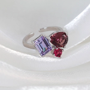 Macro shot of silver adjustable ring with purple rectangle and burgundy teardrop stones