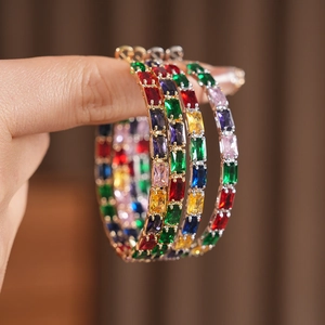 Detailed view of colorful rectangular zircon gemstones on large gold hoop earrings