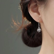 Dettaglio di orecchini a goccia in argento con zircone indossati dal modello
