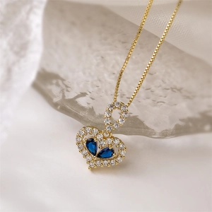 Close-up of gold heart pendant necklace with blue drop-shaped stones and clear cubic zirconia