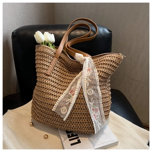 Detail of woven straw tote bag with brown leather straps and white lace floral scarf