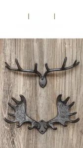 Detail of vintage cast iron antler hooks mounted on a rustic wooden texture wall