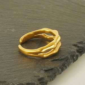 Nahaufnahme des goldfarbenen Titanstahlrings mit zweilagigem Bambus-Design auf Stein