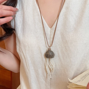 Detailed view of jelly-fish style pearl tassel necklace with brown gemstone and wax cord