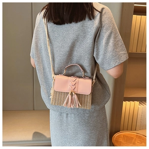 Straw crossbody bag with pink flap and tassel detail shown on model in home setting