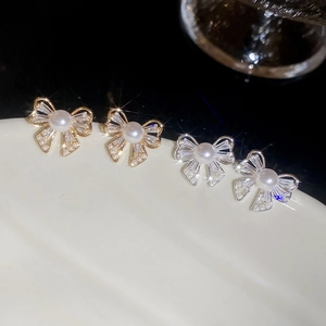 Detailed close-up of gold and silver bow pearl earrings with cubic zirconia stones