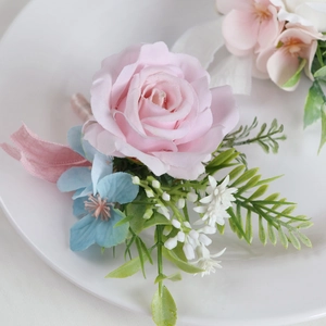 European style pink silk rose boutonniere with blue accents on a white ceramic plate