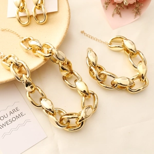 Golden chunky chain jewelry set including necklace bracelet and earrings on beige tray