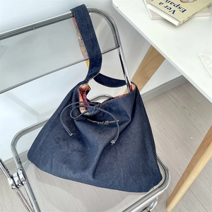 Detail of denim tote bag with ethnic print lining and gold lettering on blue fabric