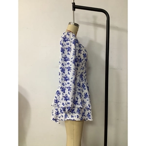 Detail of blue and white floral dress with tiered skirt layers and long sleeves