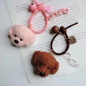 Close-up of plush teddy dog keychains with bells and heart charms in pink and brown