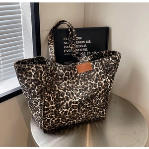 Detailed view of leopard print canvas tote bag with brown leather patch on a metal table