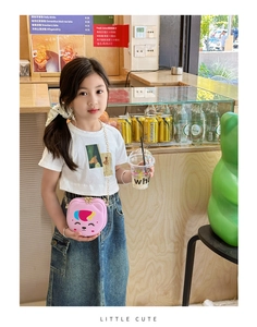 Close-up of pink cartoon crossbody bag with golden chain shown on a child model