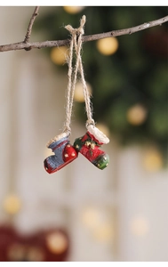 Detail of resin Christmas boot ornaments hanging on branches with warm bokeh lights