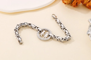 Detail of silver stainless steel chain bracelet with crystal boy and girl pendant charm