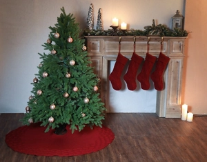 Detail of red cable-knit Christmas tree skirt and matching stockings on fireplace