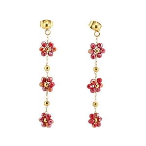 Boucles d'oreilles fleurs bohèmes en or 18 carats avec cristaux rouges sur fond blanc