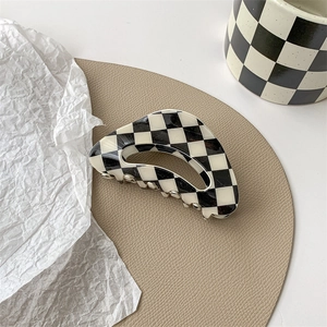 Close-up of black and white checkered hair claw clip with glossy resin finish