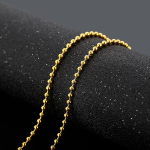 Close-up of golden beaded chain necklace wrapped around textured black display pillar