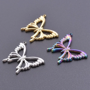 Trois pendentifs papillon en acier inoxydable or, argent et arc-en-ciel sur fond noir