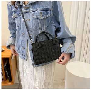 Detail of a brown woven texture crossbody bag with black leather handle on a model