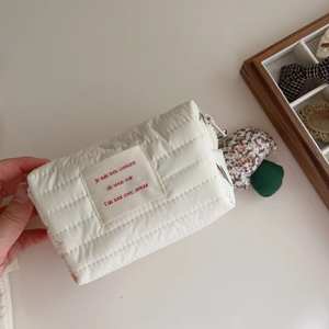 Detailed close-up of quilted cotton cosmetic bag with French embroidery and soft texture