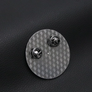Detail view of double butterfly clutch pins on the textured metal back of a badge
