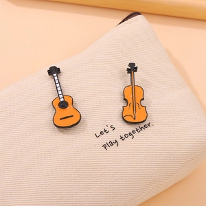 Detail of guitar and violin enamel pins with orange finish on a canvas bag