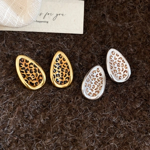 Flat lay of teardrop leopard print earrings in gold and silver finish with metal texture
