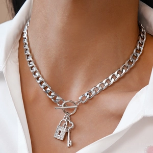 Detail of silver Cuban link necklace with rhinestone lock and key pendant on neck