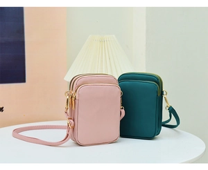 Detailed view of pink and dark green crossbody phone bags with multi-layer zippers