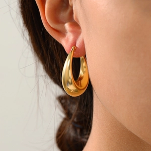 Macro shot of gold teardrop earrings in polished stainless steel on female model