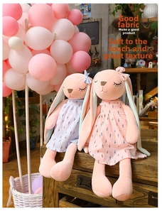 Close-up of plush rabbits in floral dresses sitting on a wooden box with soft lighting
