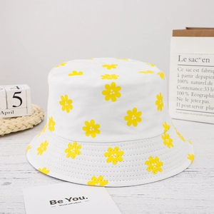 Close-up of a white cotton bucket hat with vibrant yellow floral patterns on a wooden surface