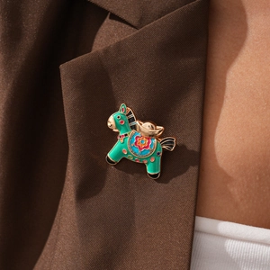 Detailed view of a green enamel horse brooch pinned on a premium brown blazer lapel