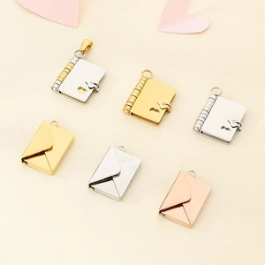 Flat lay of envelope and book pendants in gold, silver, and rose gold stainless steel