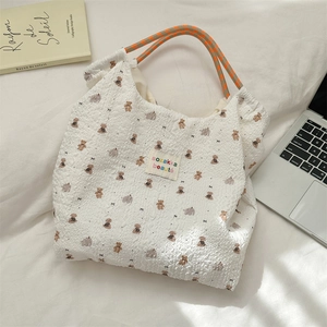 Detailed shot of white bubble textured tote bag with cute bear print and colorful handles