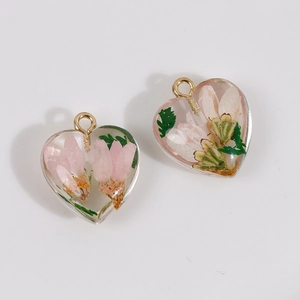 Close-up of heart resin pendants with pink dried flowers and golden loops